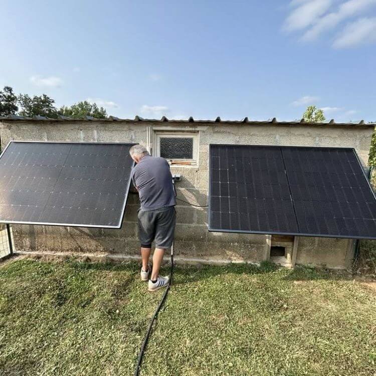 Homme qui est en train d'installer deux panneaux photovoltaïques sur un mur